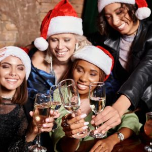 Christmas at a Dive Bar: girlfriends clinking champagne glasses while celebrating Christmas in bar